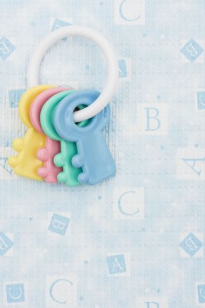 Key shaped baby rattle sitting on a blue alphabet background, baby rattleの写真素材