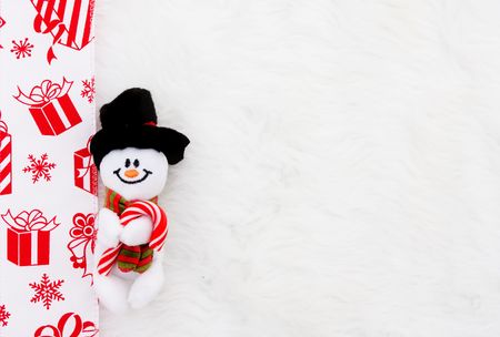 A snowman with a red present ribbon on a white fur backgroundの写真素材