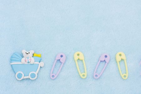 Diaper pins and a baby carriage on a blue textured background, baby borderの写真素材