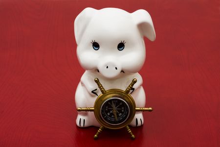 A compass sitting with a piggy bank on a red background, Navigating your financesの写真素材