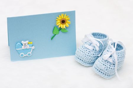 A pair of baby booties with a blank card on a white background, Welcoming a new babyの写真素材