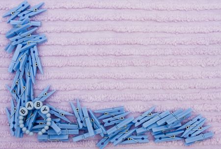 Blue clothes pins and a baby bracelet on a lavender textured background, baby borderの写真素材