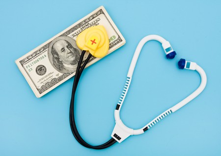 A toy stethoscope with money on a blue background, medical costsの写真素材