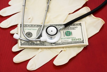 A stethoscope with money on a wooden background, Medical Costsの写真素材