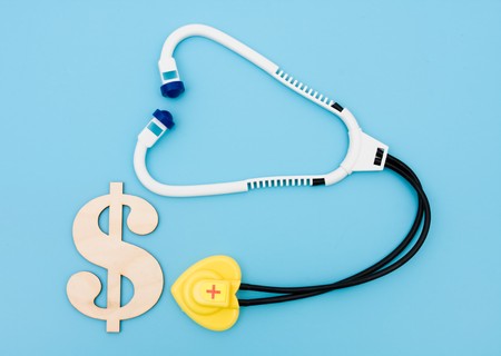 A toy stethoscope with a dollar sign on a blue background, medical costsの写真素材