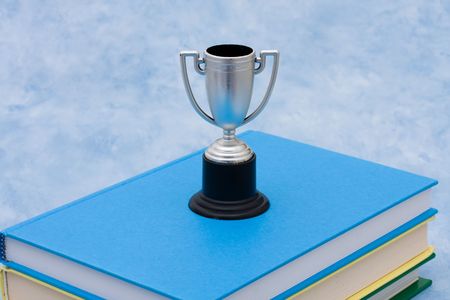 A stack of book with a trophy on a blue background, education awardの写真素材