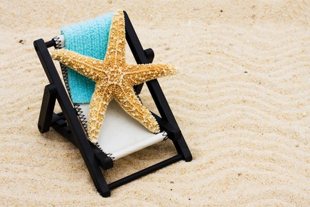 A lounge chair with starfish on a sand background, Relaxing on Vacation の写真素材