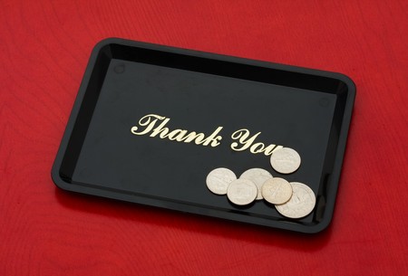 Silver coins on a black tray on a wood background, tip moneyの写真素材