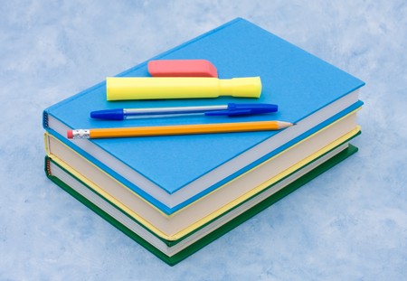 A stack of book with a pen, pencil, eraser and highlighter on a blue background, School Suppliesの写真素材