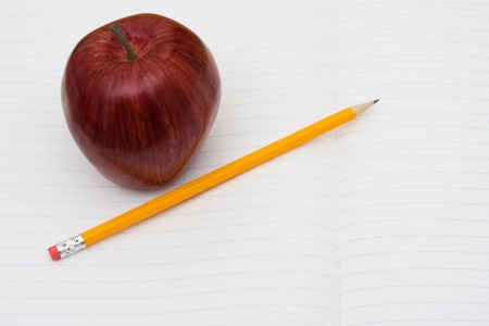 A pencil on a workbook with an apple, school workの写真素材