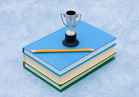 A stack of book with a trophy and a pencil on a blue background, education awardの写真素材