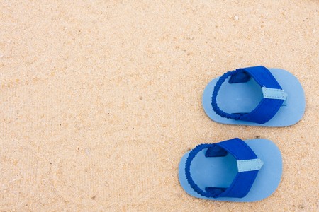 A starfish and a pair of babys sandals sitting on a sand background, beach babyの写真素材
