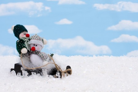 Two snowmen sitting on a sleigh with a sky background, snowmanの写真素材