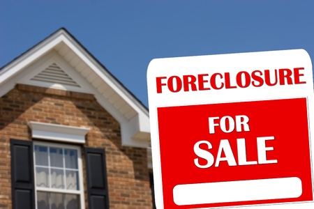 A red and white for sale sign with a brick house in backgroundの写真素材