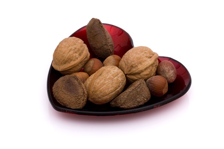 A heart shaped dish of healthy mixed nuts in shell isolated on white, healthy eating