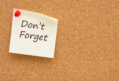 A sticky note on a corkboard with the words donï¿½t forget on itの写真素材