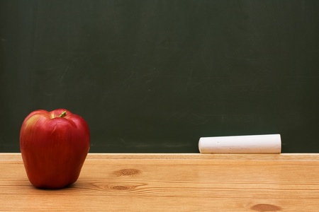 Apple on a desk in front of a chalkboard with copy space, School Daysの写真素材