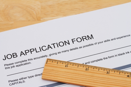 A job application form with a ruler on a wooden desk, How you measure up when applying for a jobの写真素材