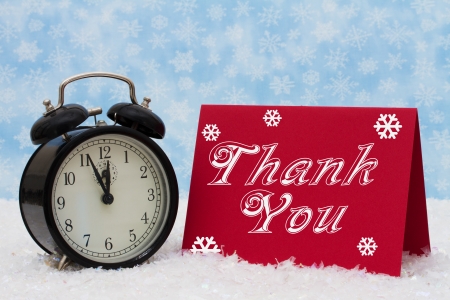 An old-fashion alarm clock with a Thank You red card on snow and a blue snowflake background, Christmas is a Time to be Thankfulの写真素材
