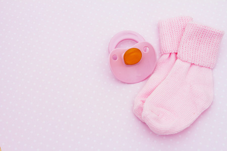 Pink Baby Background, Pink baby socks with soother on pink and white polka dot background with...
