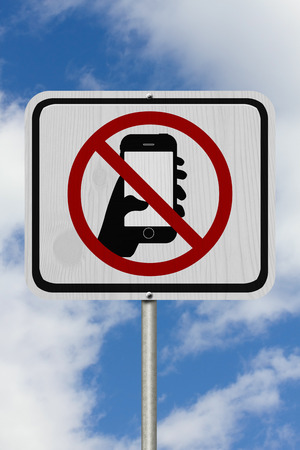 No Texting Road Sign,  A white Road Sign with symbol of hand and mobile phone with sky backgroundの写真素材