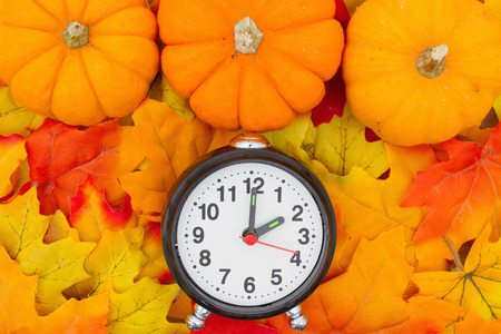 Some fall leaves and a pumpkins with a alarm clockの写真素材