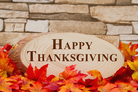 Some fall leaves and wood plaque on weathered brick with text Happy Thanksgivingの写真素材