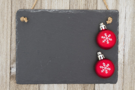 Old fashion Christmas hanging chalkboard background, A retro chalkboard with Christmas ornaments hanging on weathered wood background with copy space for your messageの写真素材