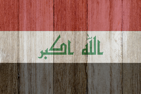 A rustic old Iraqi flag on weathered wood for a backgroundの写真素材