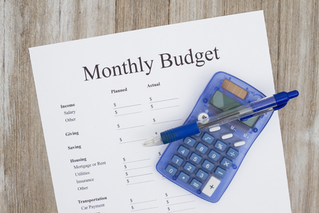 Creating a monthly budget, A print out of a monthly budget with pen and calculator on weather woodの写真素材