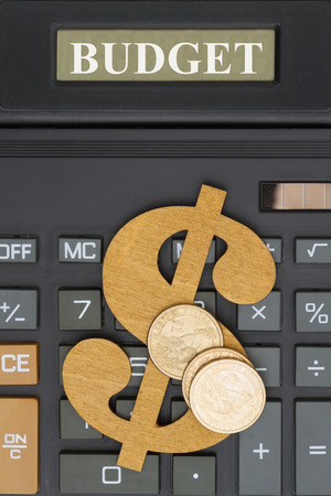 Budget text on the display of a close-up of a calculator with a dollar sign, gold coinsの写真素材