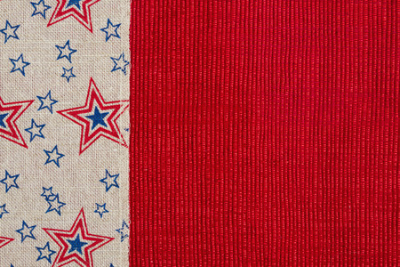 Red and blue star burlap ribbon on a shiny red material on a shiny red material with copy space for...