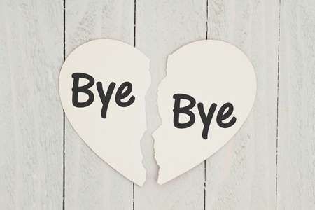 Heart-shape card on weathered wood background with text Bye Bye on each piece of the cardの写真素材