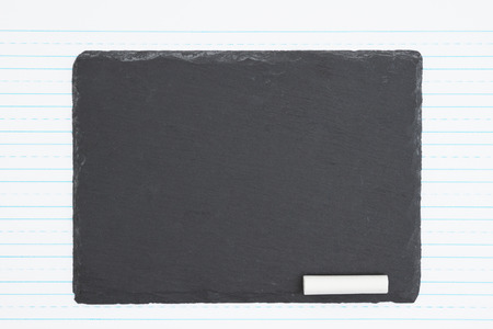Retro lined paper and weathered old chalkboard and piece of chalk with copy space for your message