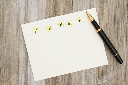 A blank greeting card on weathered wood and a pen and five good stars with copy space for your messageの写真素材