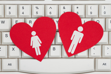 Finding love on the Internet, A close-up of a keyboard with two red hearts with a man and a womanの写真素材