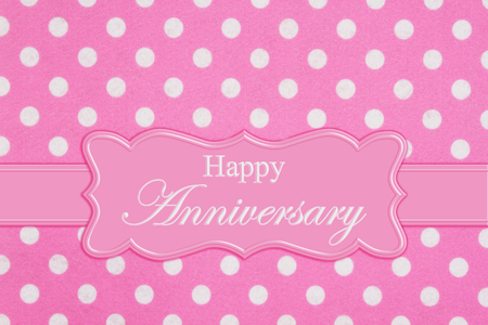 Happy Anniversary greeting on a ribbon with bright pink and white polka dot felt textured fabricの写真素材