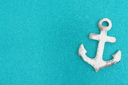 Weathered anchor on a turquoise glitter background with copy space for your your seaside or beach messageの写真素材