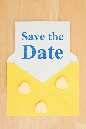 Save the Date message on white card and hearts with a yellow envelope on a deskの写真素材