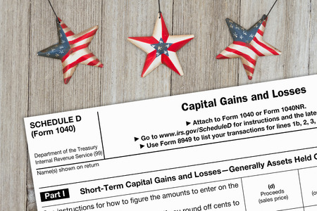 A US Federal tax 1040 schedule D income tax form on weathered wood with USA starsの写真素材