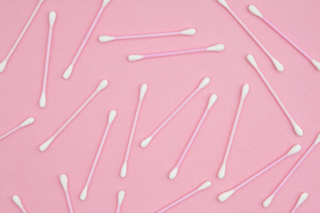 White and pink cotton swabs on pink paper to use for a health or beauty backgroundの写真素材