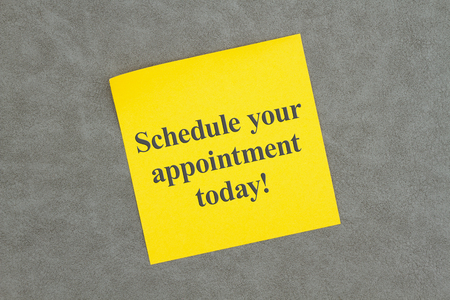 Schedule your appoint today text on a message on a sticky note on textured gray leatherの写真素材