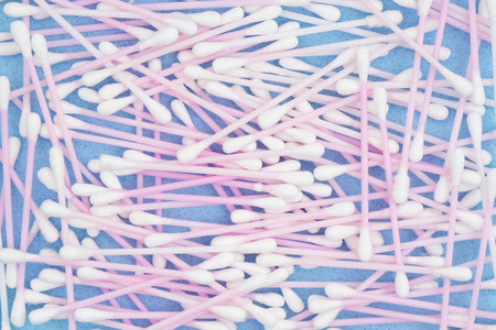 White and pink cotton swabs on blue paper to use for a health or beauty background