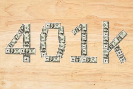 Retirement 401k text made from 100 dollar bills on a wood desk