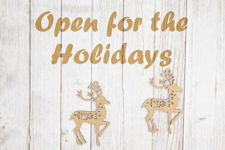 Open for the holidays text with wood reindeer on weathered whitewash textured wood