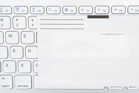 Close-up of a light gray computer keyboard with blank envelope for your message