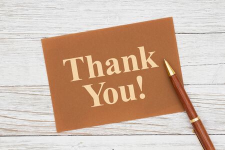 Thank you message on brown greeting card with pen on a weathered whitewash woodの写真素材