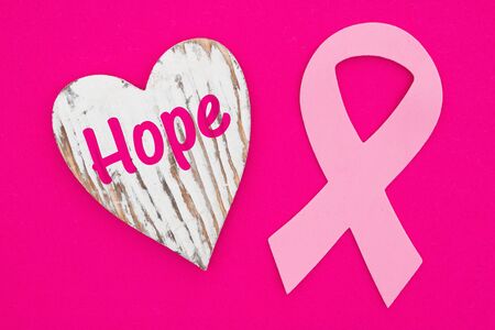 Hope message on weathered heart with pink cancer ribbon on bright pink textured felt materialの写真素材