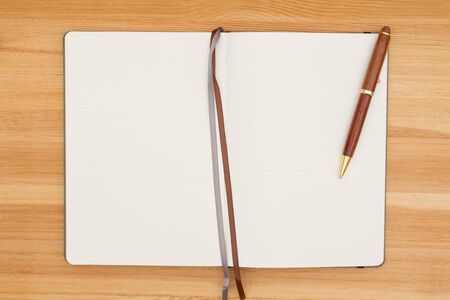 Blank journal  with pen on a wood desk with copy space for your message