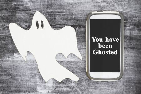 You have been ghosted message with a white ghost and cell phone on weathered black grunge wood